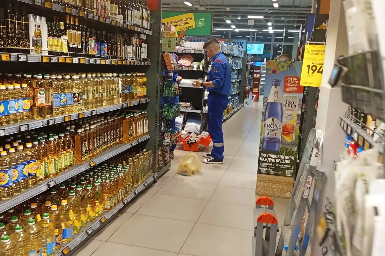 Поврежденное оборудование и товары в супермаркете после инцидента, на заднем плане видны сотрудники.